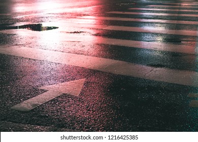 The Red Traffic Light On A Crosswalk At Night On Wet Asphalt