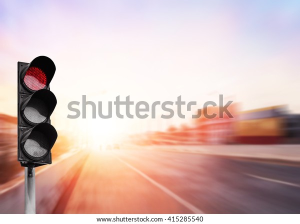Red traffic light on the expressway asphalt road\
with car in a city landscape at sunrise. light sign for car stop\
and speed reduction. Dangerous,warning signal,semaphore. Driving on\
a Highway.