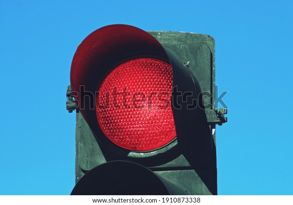 Red traffic light on San Modesto street in\
Madrid, Spain. Close-up of red traffic light for cars with a blue\
sky in the background.