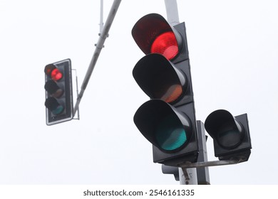Señal roja del semáforo. Intersección lluviosa del día brumoso. Semáforo inteligente. Cruce de la ciudad con semáforo. Mal tiempo en las condiciones de la carretera. Cielo gris y baja visibilidad.