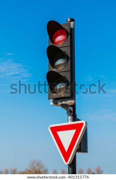red traffic\
light with yield sign on blue\
sky
