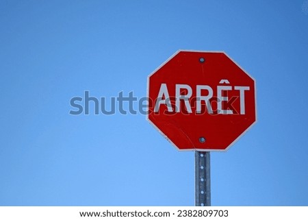 A red traffic sign on a blue sky background. French Canadian sign for Stop.