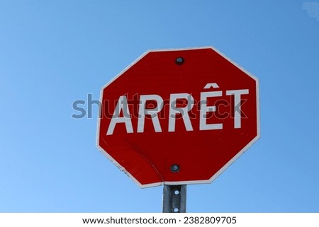 A red traffic sign on a blue sky background. French Canadian sign for Stop.