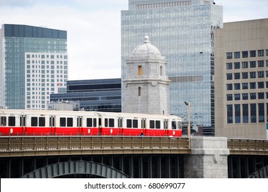 red train crossing long field bridge above Charles river in Boston