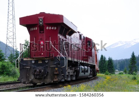 red train driving through the rockies