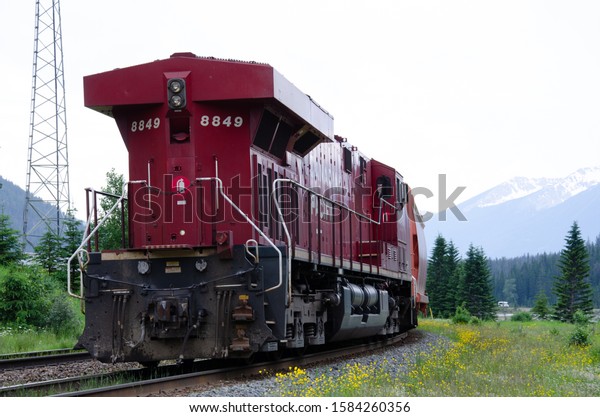 red train driving\
through the rockies