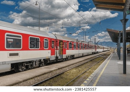 Red train in train station, empty platform, on background Slovakia mountains. 