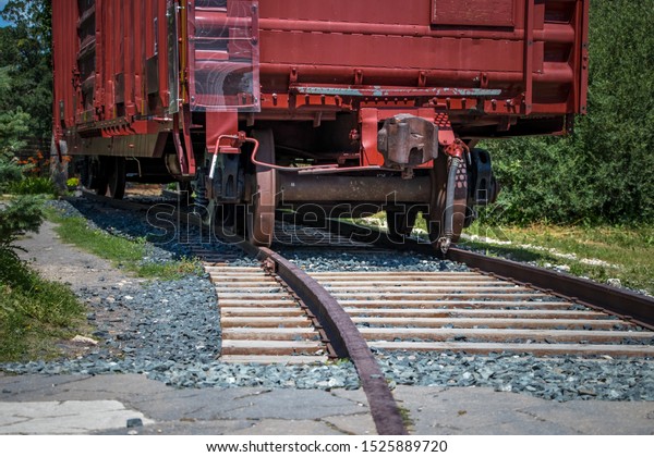 A red train wagon parked on railway tracks. A\
perspective image.