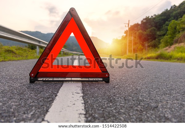 Red triangle, red emergency\
stop sign, red emergency symbol on road with sun light\
background.