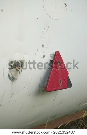 Red triangle reflector on a damaged white trailer panel with exposed wire