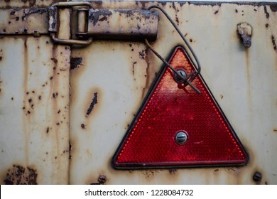 Red Triangle Shaped Safety Reflector On Rusty Metal Surface