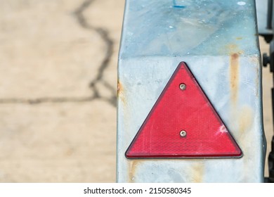 Red Triangle Shaped Safety Reflector On Rusty Metal Surface