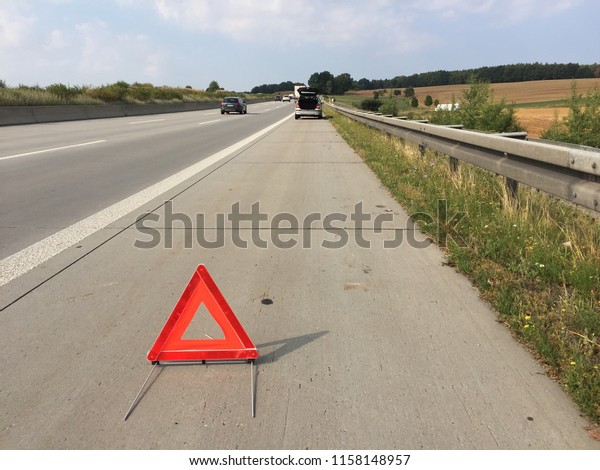 Red triangle warning sign and\
broken down car in the distance, diminishing\
perspective