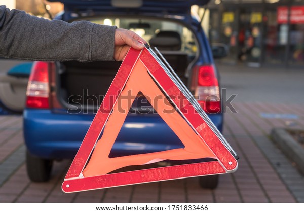Red triangle warning sign and broken down car in\
the distance