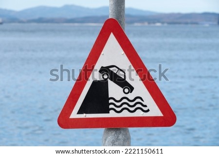 Red triangle warning sign making drivers aware that vehicle could fall into deep water.