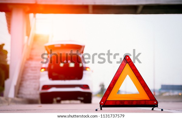 Red triangle warning sign on the road,car with\
breakdown alongside the\
road.