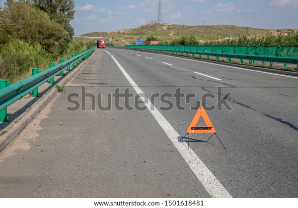 a red triangle warning sign on the road,\
indicating a car of problems
