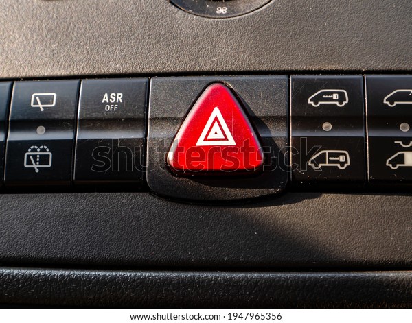 Red triangular car alarm button on the dashboard.\
Car alarm. Red button. Triangular shape. The profession is a\
vehicle driver. Vehicle driving. Control Panel. Abnormal road\
situation. Warning signal.