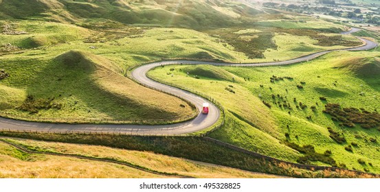 Red Truck On Serpentine Road Among Green Landscape Of Peak District National Park In UK