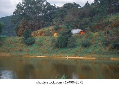 Red Truck Passing Through Dirt Road Beside Lake