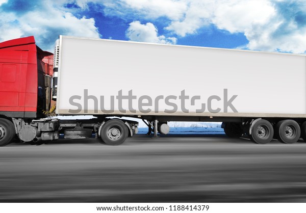 Red truck and a white trailer with space for text\
driving fast on the winter countryside road with snow against blue\
sky with clouds