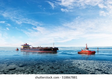 Red Tugboat Towing A Tanker Ship At Winter.