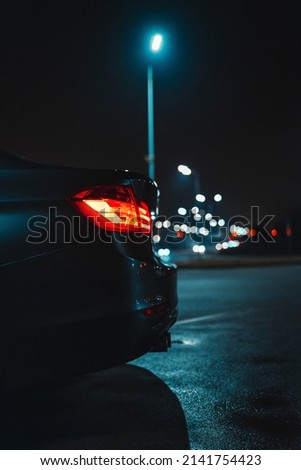 The red turn on headlight of a modern car is on the night street. Bokeh of the city lighning on the background