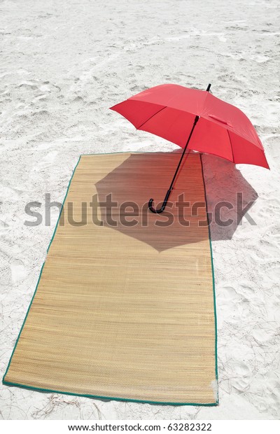 Red umbrella and\
bamboo mat on the beach