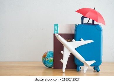 Red umbrella cover airplane, passport, flight tickets and suitcases travelers on wooden background. Travel insurance covers loss suitcase, flight delays, cancellations, accident and medical expenses.