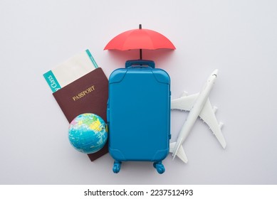 Red umbrella cover airplane, passport, globe, flight tickets and suitcases travelers on white background. Travel insurance covers loss suitcase, flight delays, cancellation, accident, medical expenses - Powered by Shutterstock