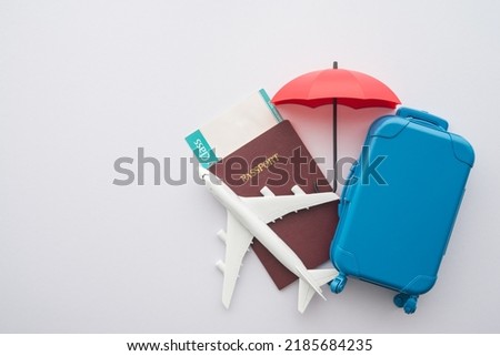 Red umbrella cover airplane, passport, flight tickets and suitcases travelers on white background. Travel insurance covers loss suitcase, flight delays, cancellations, accident and medical expenses.