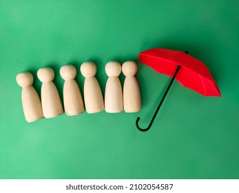 Red Umbrella With Peg Doll Arrangement To Protect Wooden Peg Doll, Plan, Save Family, Prevent Risk And Crisis, Health Care And Insurance Concept.