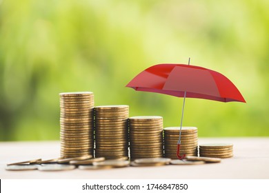 Der rote Schirm schützt die Reihen der wachsenden Münzen auf dem Tisch. Konzeption langfristiges Geld- und Vermögensmanagement mit Risikoschutz, finanzielle Darstellung der Sicherung von Vermögenswerten für nachhaltiges Wachstum