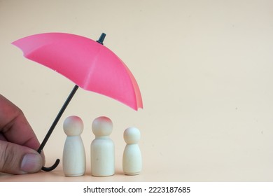 Red umbrella with wooden family peg dolls for protection with copy space. Family protection and insurance coverage concept. The insurance agent presents protection model that symbolize the coverage. - Shutterstock ID 2223187685