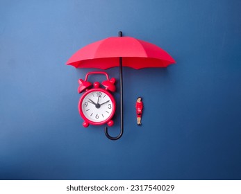 Red umbrella,clock and miniature people on a blue background