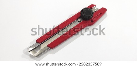 A red utility knife with an adjustable blade and a black locking wheel.