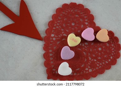 A Red Valentine Doily With A Close Up Of Candy Hearts, One Reads Laugh, A  Pointed Arrow From The Side