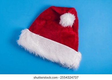 Red velour Santa hat on blue background - Powered by Shutterstock