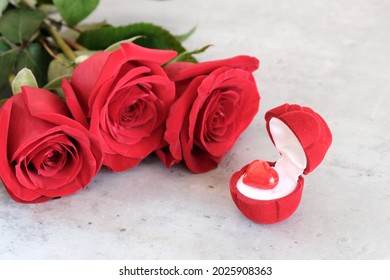 Red velvet box with a heart on a light background next to a bouquet of red roses. Marriage proposal, declaration of love, valentine's day concept - Powered by Shutterstock