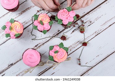 Red Velvet Cupcakes Decorated With Sisal Lace, Surrounded By A Female Necklace. Confectioner Decorating A Cupcake (top View).