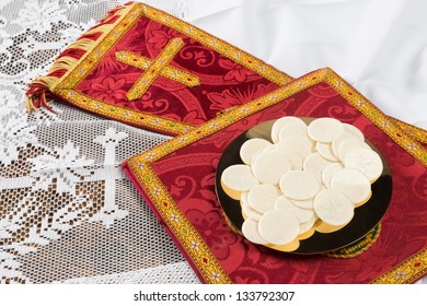 Red vestment set and communion hosts on a golden plate