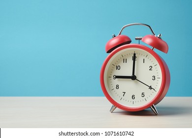 Red vintage alarm clocks on wooden table and light blue background wall - Shutterstock ID 1071610742