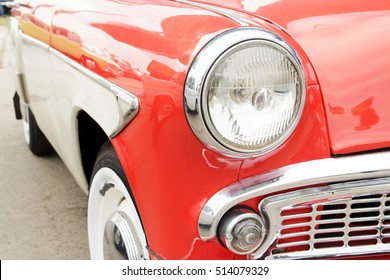 Red vintage car on a festival of old cars. Retro car's headlight close up.