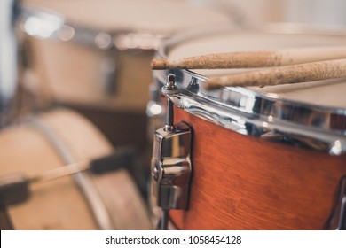 Red vintage drums, drum sticks, snare, hi-hat, bass drum in the house with stripped colorful carpet 