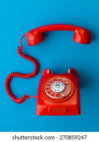 Red Vintage Phone With Handset Off The Hook, On Blue Background