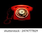 red vintage telephone, with dial for dialing numbers and coiled cord, isolated on black background