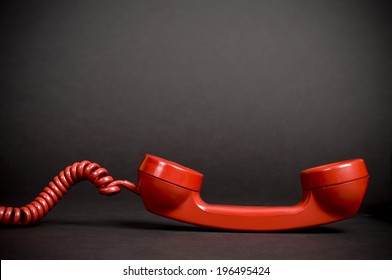 A Red Vintage Telephone Receiver With A Spiral Cord.