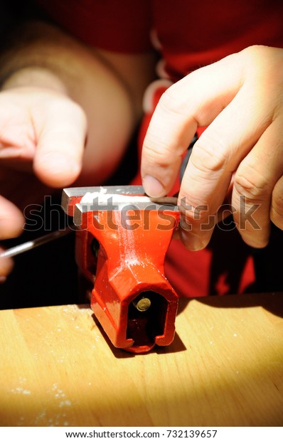 Red vise and hands of handy man working in
workshop with workbench
