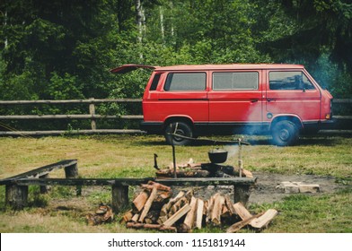 Red volkswagen transporter 3. Volkswagen T3 is standing in forest on green background. Hippie vintage auto 1979 of issue. Retro car. Bonfire, firewood and pot. Tourism and travel. Rest in the forest.
