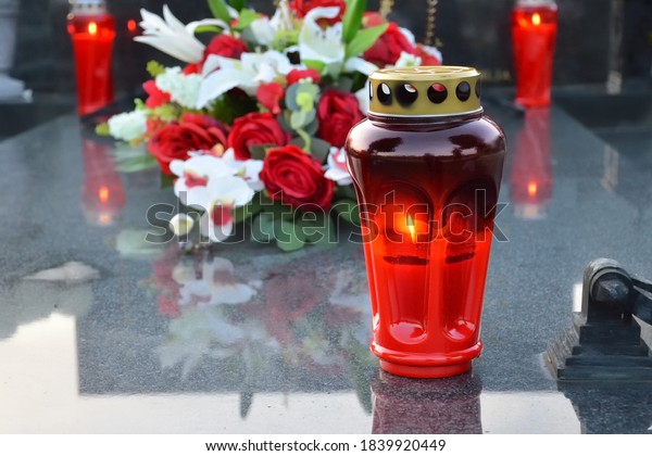 Red votive candle on the\
grave 